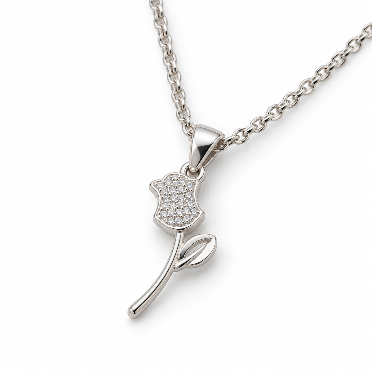Second angle: Angled view of silver rose pendant showing its clear-stone flower, open leaf, and curved stem