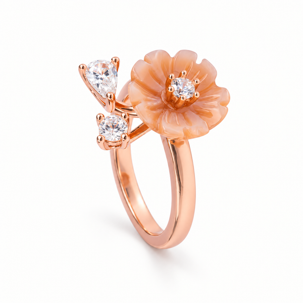 A rose gold ring featuring a sculpted peach flower and two pear-cut clear gemstones on a white background.