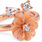 Close-up: Close-up of translucent peach flower, pear-shaped stone and round clear stones on rose-gold ring