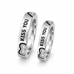 A pair of silver-toned couple's rings engraved with 'KISS YOU' and accented with heart-shaped clear crystals, shown on a clean white background.