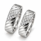 Close-up: Close-up of three clear-stone rows and diagonal detailing on matching silver couple rings