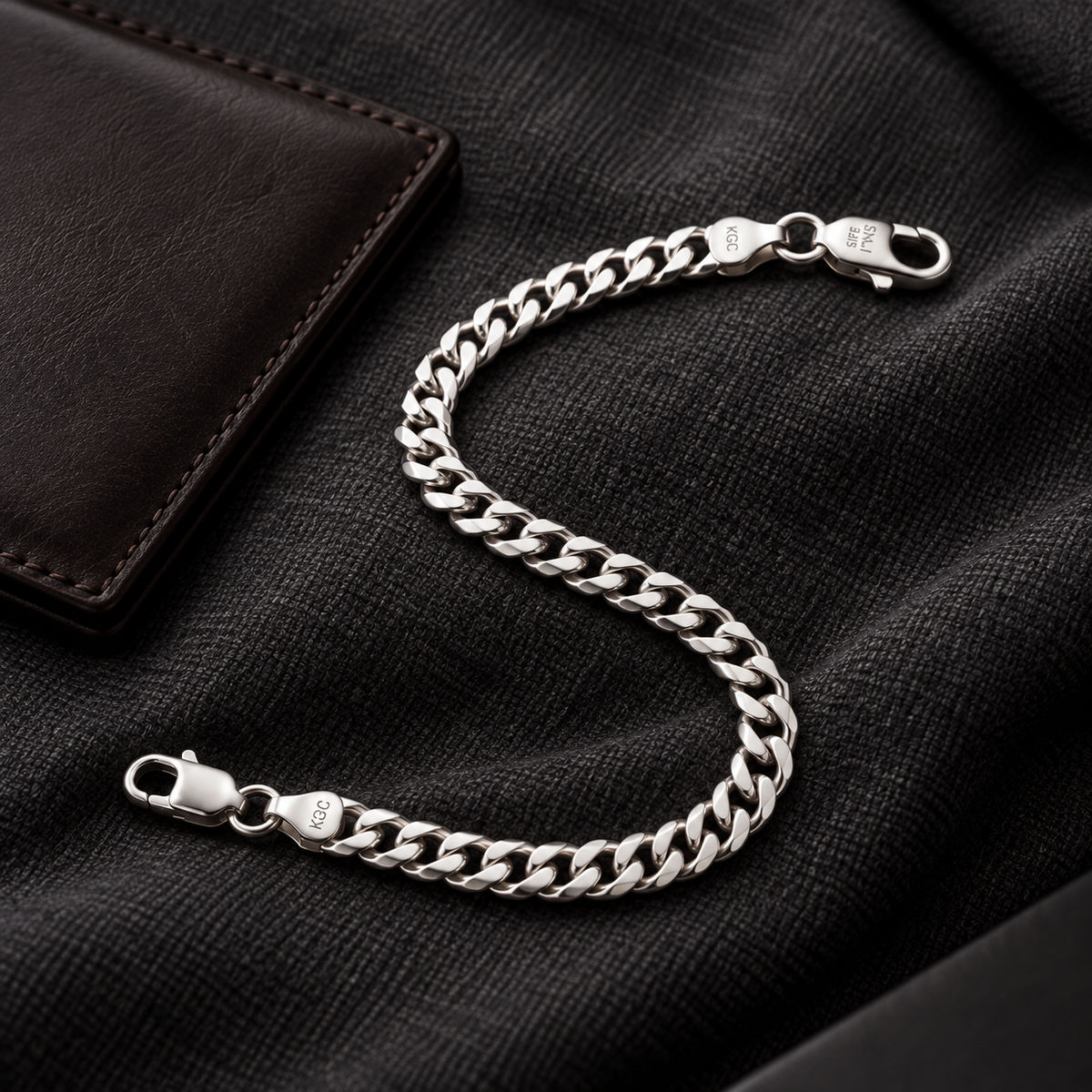 Men’s silver curb bracelet styled with a dark outfit and leather accessory
