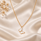 Gold-tone white butterfly necklace styled on soft ivory fabric  
