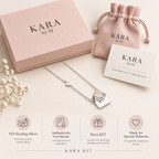 A silver heart-link necklace with a heart-shaped pendant engraved with 'KARA by SJ' is displayed with its pink gift box, matching drawstring pouch, and authenticity certificate on a light beige background. Four circular icons at the bottom highlight product features: 925 sterling silver, authenticity certificate, Kara KIT, and made for special moments.
