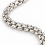 A close-up of a polished silver-toned metal link chain bracelet or necklace arranged in a curved loop on a clean white background.