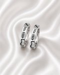 Two silver rings with 'KISS YOU' text and heart-shaped crystal details, displayed on a white satin background.