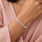 Lifestyle image: Floral silver bracelet styled on soft blush fabric with an elegant outfit  