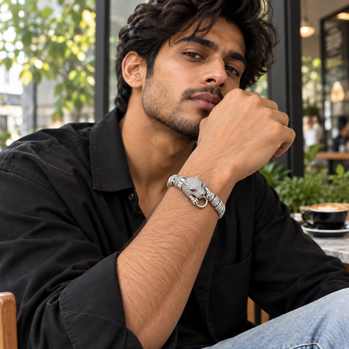 Young man styling a silver panther bracelet with a modern black outfit.